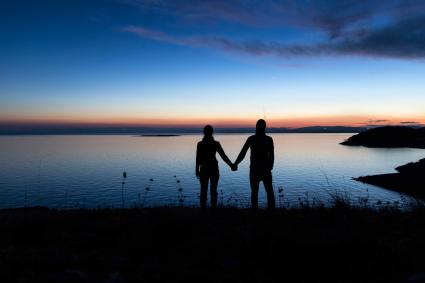 Silhouette de couple main dans la main au coucher du soleil 