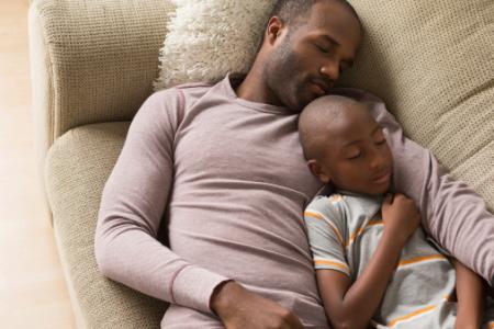 Père et fils dormant sur un canapé