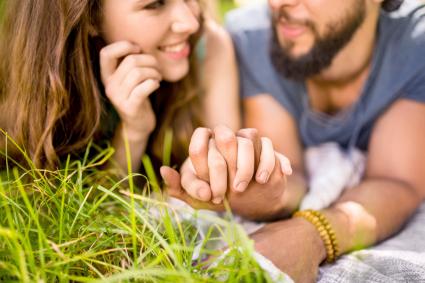 Couple affectueux se tenant la main en position couchée sur l'herbe