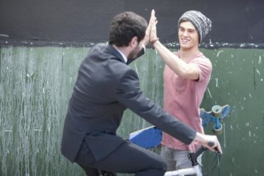 Skateboarder and businessman in suit high five
