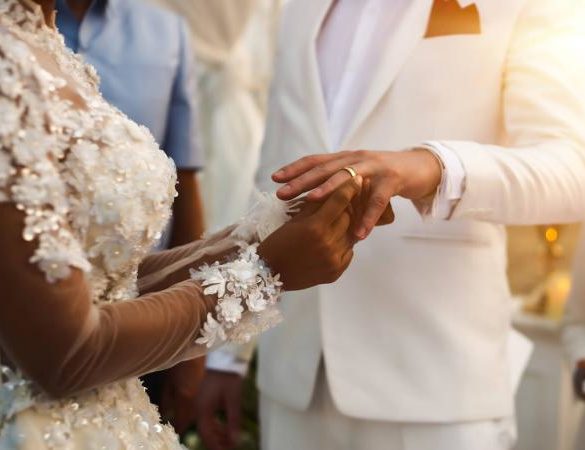 bride putting ring on grooms finger