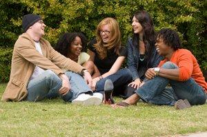 Groupe d'amis assis sur l'herbe et riant