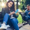 Young couple in the park texting