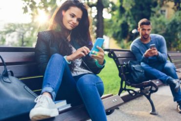 Young couple in the park texting