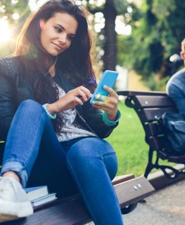 Young couple in the park texting