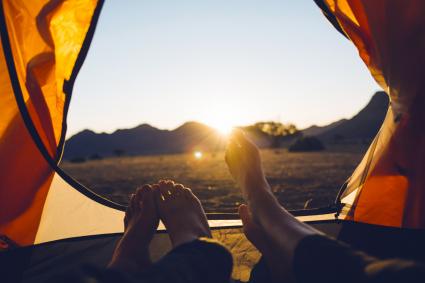 Couple regardant le soleil se coucher depuis la tente