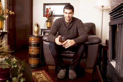 Homme assis avec un verre dans une pièce brune