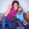 African couple cheering on sofa