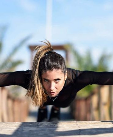 woman doing push-ups on wooden bridge