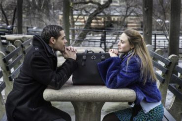 Man and woman staring at each other across table outdoors