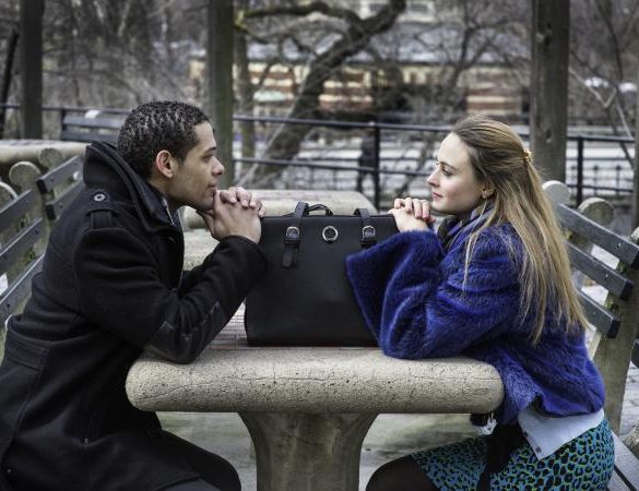 Man and woman staring at each other across table outdoors