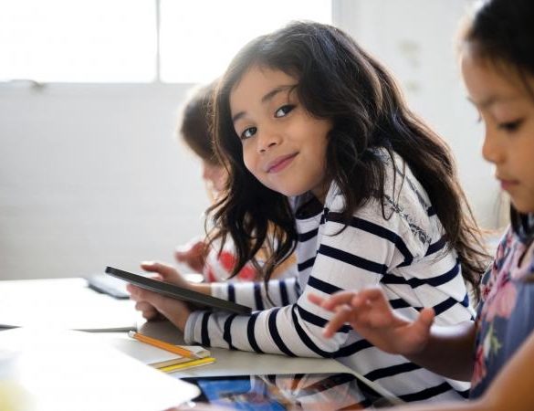 Portrait of smiling girl using digital tablet in classroom