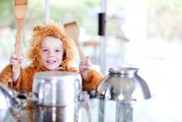 Boy dressed as a lion pretending to be drummer