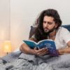 Man reading horoscope in bed