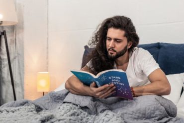 Man reading horoscope in bed