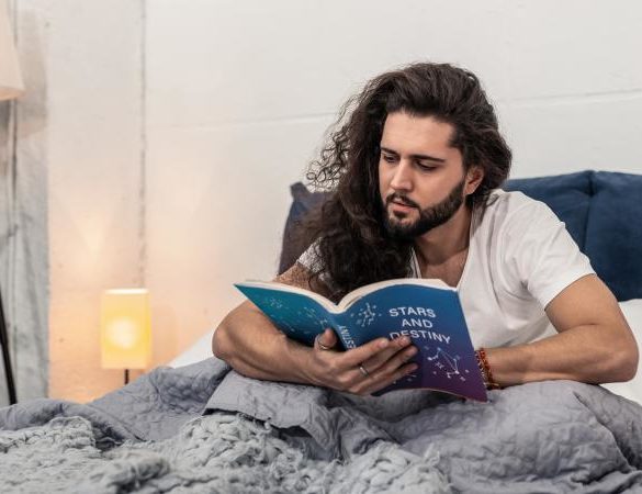 Man reading horoscope in bed