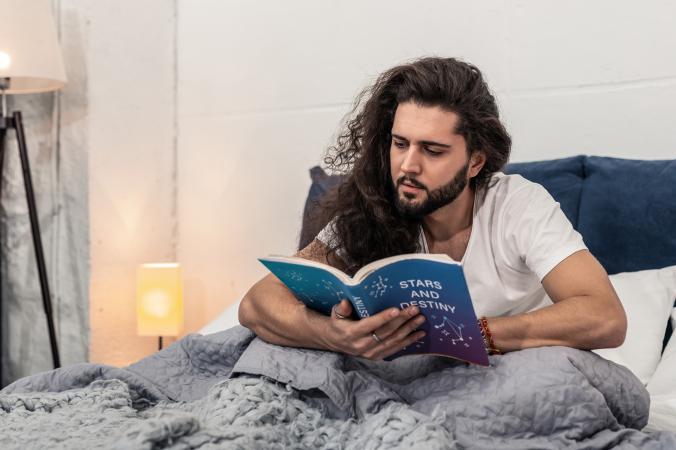 Homme lisant l'horoscope au lit