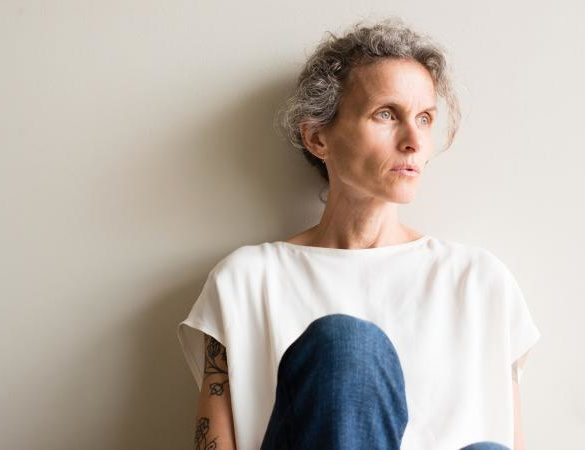 Woman sitting with back to wall