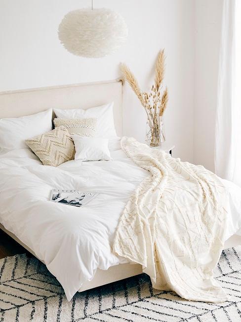 lit avec linge blanc, coussins et plaid beige, suspension nuage et herbe de la pampa séchée